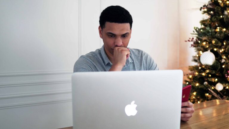 Man worriedly staring at a MacBook.
